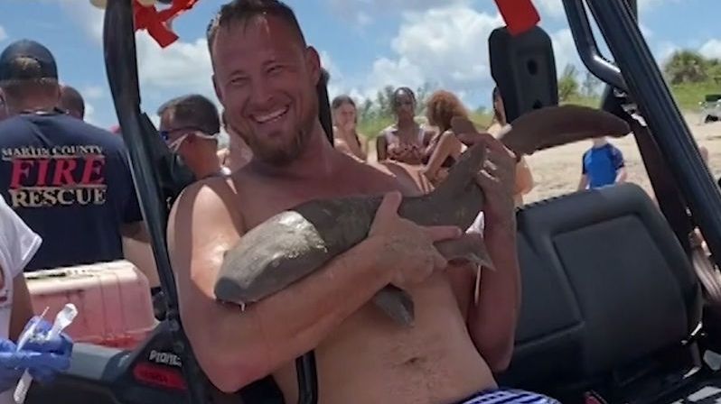 Muž vylezl z vody se žralokem zakousnutým v ruce
